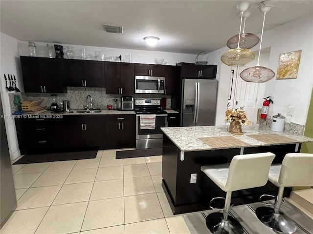 kitchen featuring tasteful backsplash, sink, a kitchen bar, light tile patterned floors, and stainless steel appliances