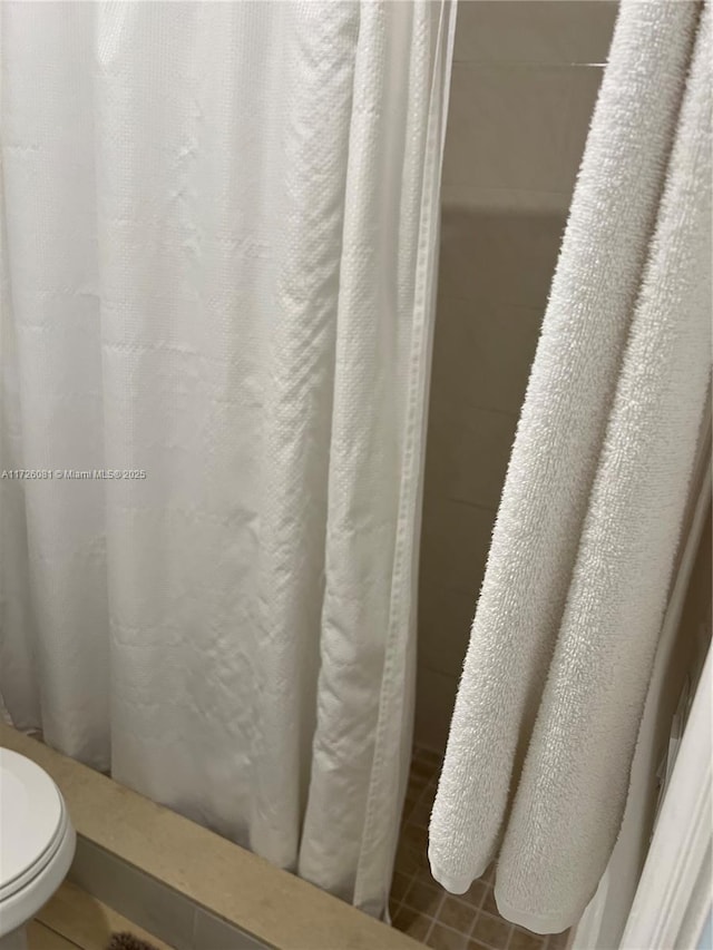 bathroom with toilet and a shower with shower curtain