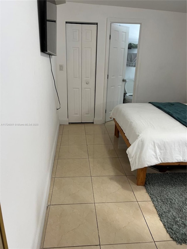 tiled bedroom with ensuite bathroom and a closet