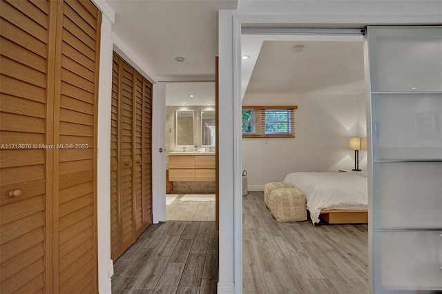 bedroom with light wood-type flooring and ensuite bath