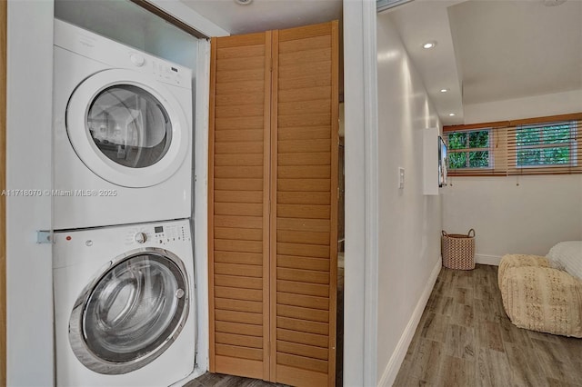 washroom featuring stacked washer and clothes dryer and light wood-type flooring