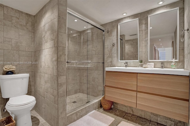 bathroom with vanity, a shower with shower door, tile walls, and toilet