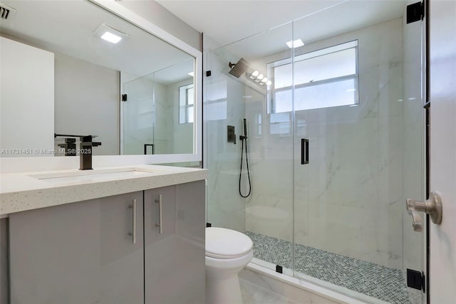 bathroom featuring vanity, a shower with shower door, tile patterned floors, and toilet