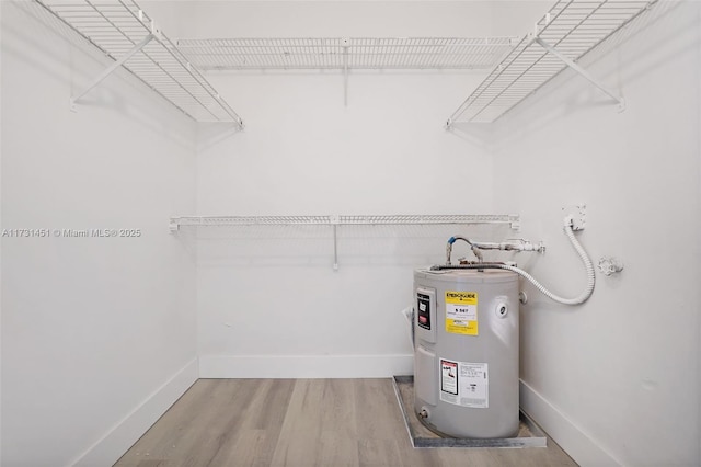 spacious closet with electric water heater and hardwood / wood-style floors