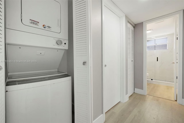 laundry room with stacked washing maching and dryer and light wood-type flooring