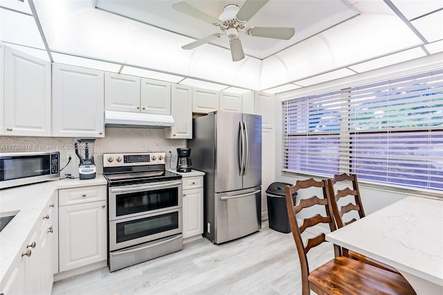 kitchen with white cabinetry, stainless steel appliances, light hardwood / wood-style floors, and light stone counters