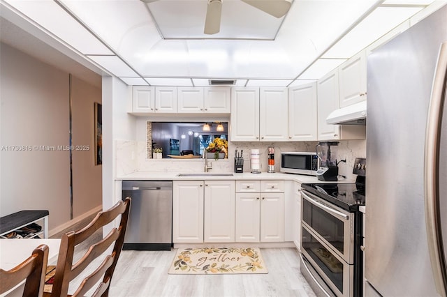 kitchen with sink, white cabinets, ceiling fan, stainless steel appliances, and backsplash