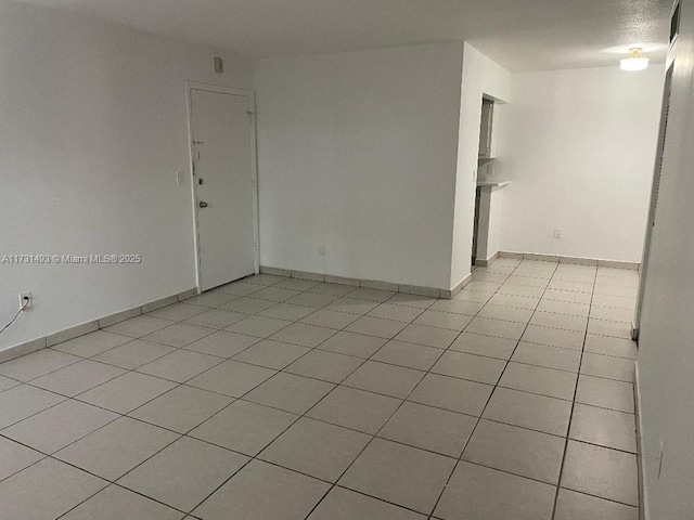 spare room featuring light tile patterned floors and baseboards