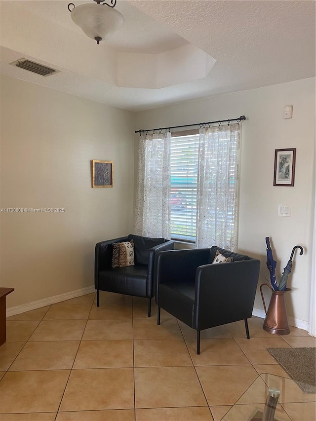 tiled living room with a tray ceiling and a textured ceiling