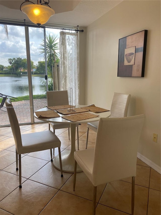 tiled dining room with a water view and floor to ceiling windows