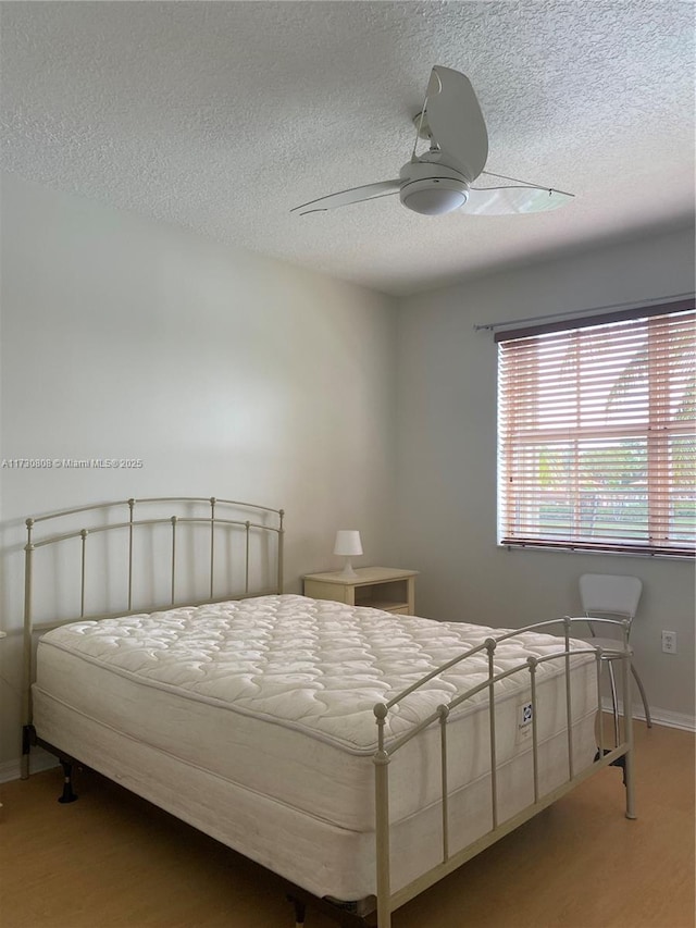 bedroom featuring ceiling fan, hardwood / wood-style floors, and a textured ceiling