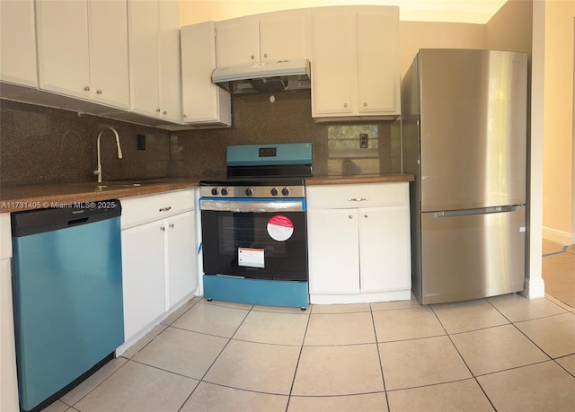 kitchen with tasteful backsplash, appliances with stainless steel finishes, light tile patterned floors, and white cabinets