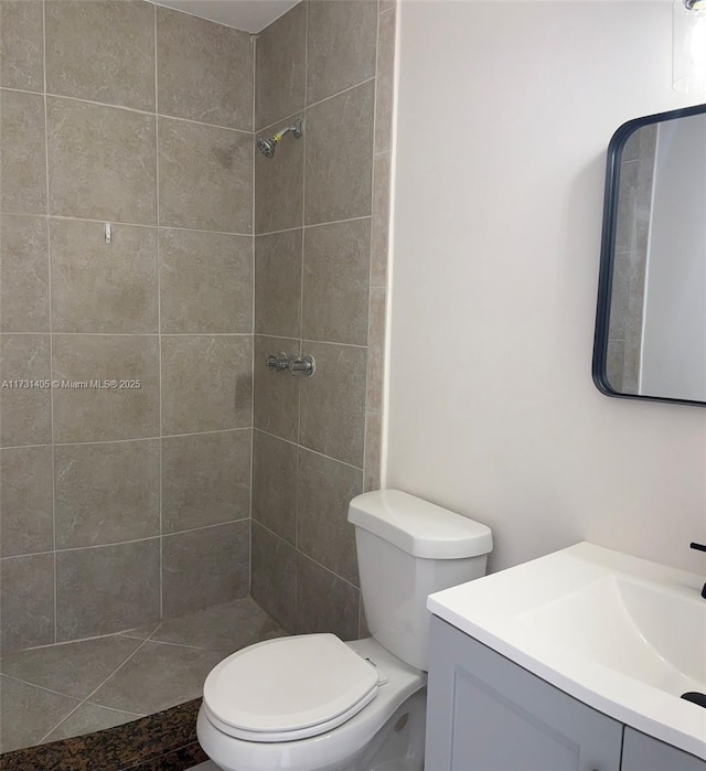 bathroom featuring vanity, tiled shower, and toilet