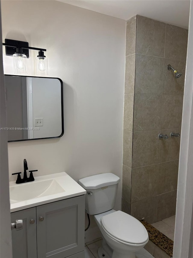 bathroom with vanity, tile patterned flooring, toilet, and a tile shower