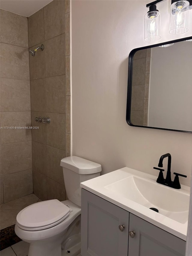 bathroom featuring vanity, toilet, and a tile shower