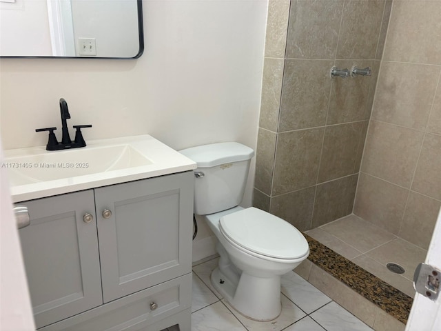 bathroom featuring vanity, toilet, and a tile shower