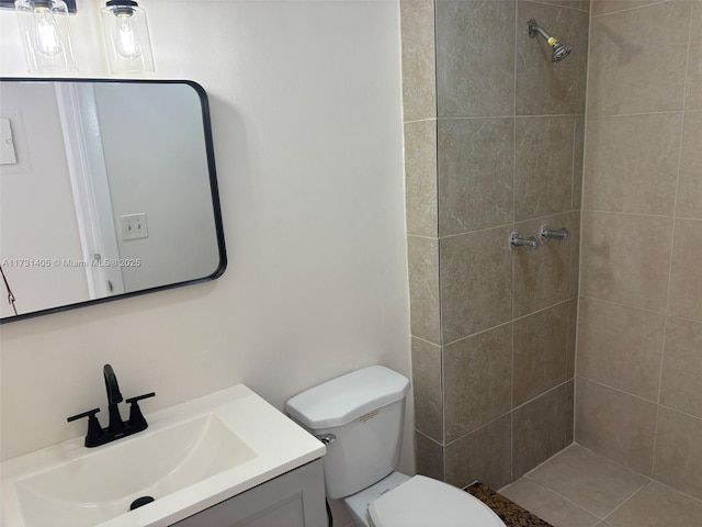 bathroom with vanity, toilet, and tiled shower