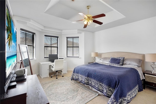 carpeted bedroom with a tray ceiling and ceiling fan