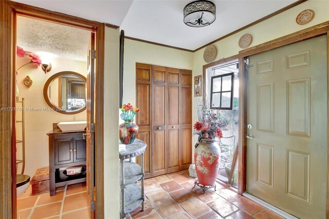 entryway featuring crown molding, sink, and a textured ceiling