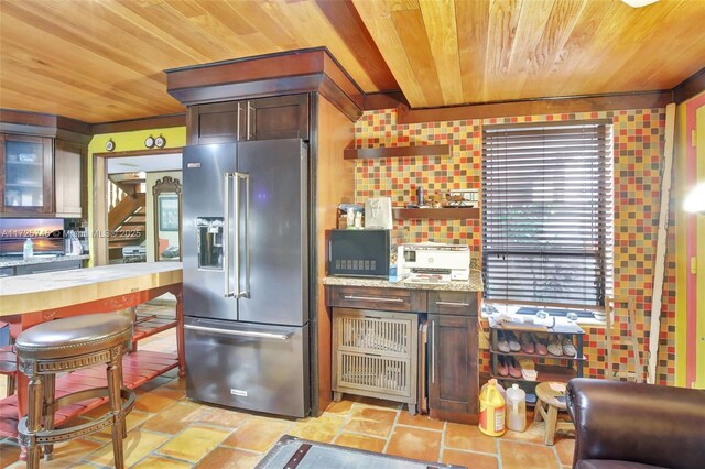 kitchen featuring dark brown cabinets, high end fridge, light stone counters, and plenty of natural light