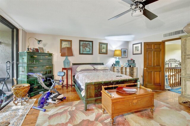 bedroom with light wood-type flooring, a textured ceiling, ceiling fan, and a wall of windows