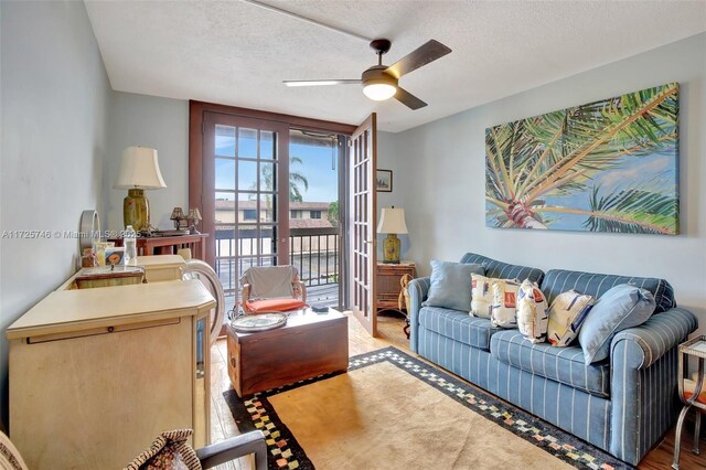 living room featuring ceiling fan and a textured ceiling