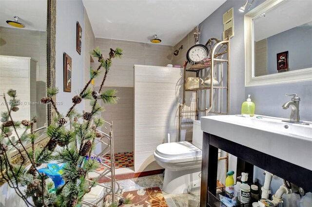 bathroom with a tile shower, vanity, and toilet