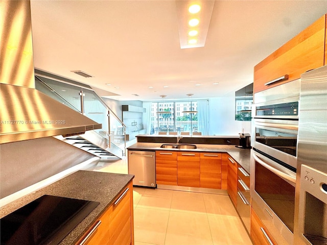 kitchen with dark stone countertops, stainless steel appliances, sink, and light tile patterned floors