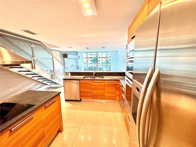 kitchen featuring light tile patterned flooring, appliances with stainless steel finishes, sink, and dark stone counters