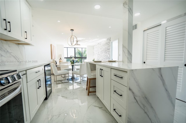 kitchen featuring stainless steel electric stove, decorative light fixtures, white cabinetry, beverage cooler, and light stone counters