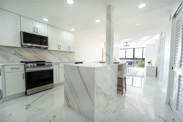 kitchen with stainless steel appliances, white cabinetry, tasteful backsplash, and a wall of windows