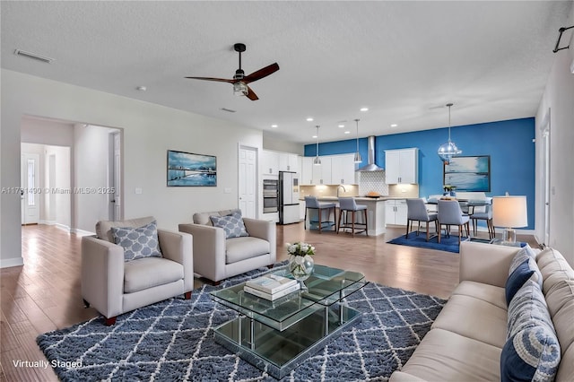 living room with dark wood-type flooring, ceiling fan, sink, and a textured ceiling