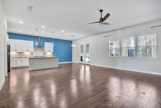 unfurnished living room featuring sink, a textured ceiling, dark hardwood / wood-style flooring, ceiling fan with notable chandelier, and french doors