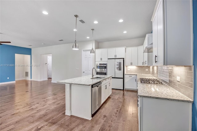 kitchen with white cabinetry, stainless steel appliances, decorative light fixtures, and a center island with sink