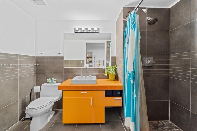 bathroom featuring tile walls, a shower with shower curtain, vanity, tile patterned floors, and toilet