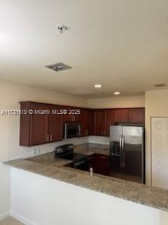 kitchen with light stone counters, kitchen peninsula, and appliances with stainless steel finishes