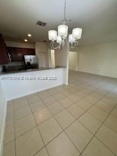 kitchen with dark brown cabinets, hanging light fixtures, stainless steel refrigerator, light tile patterned floors, and a notable chandelier