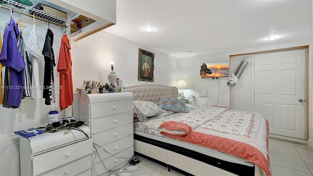 bedroom with crown molding, light tile patterned flooring, and a closet