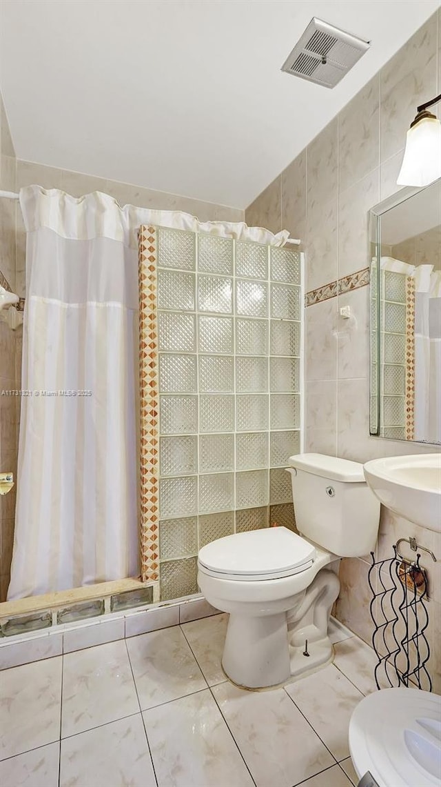 bathroom with tile patterned floors, toilet, curtained shower, and tile walls