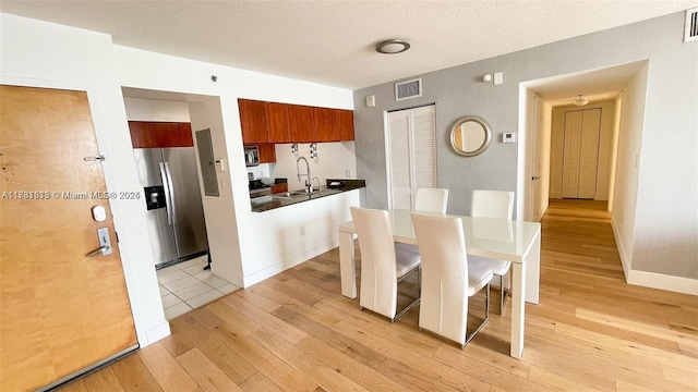 dining space featuring sink, light hardwood / wood-style floors, and a textured ceiling