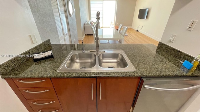 kitchen with dark stone countertops, sink, and stainless steel dishwasher