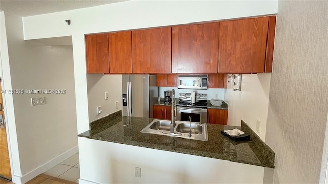 kitchen with dark stone countertops, light tile patterned floors, stainless steel appliances, and kitchen peninsula