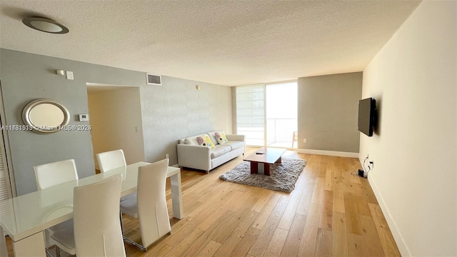 living room featuring light hardwood / wood-style floors, floor to ceiling windows, and a textured ceiling