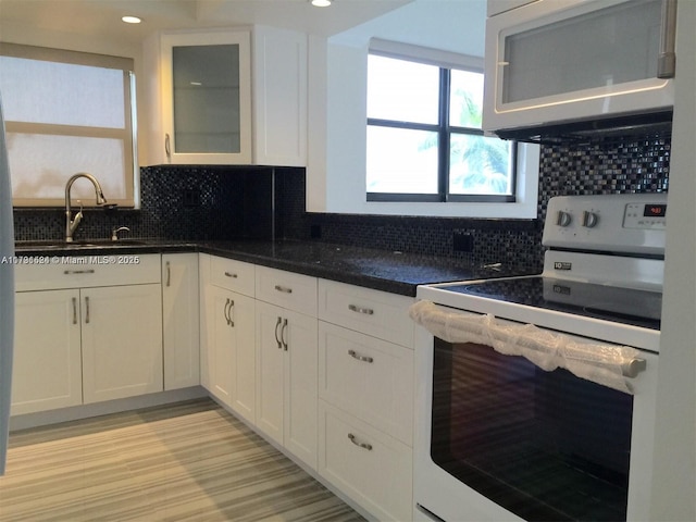 kitchen featuring tasteful backsplash, sink, white cabinets, and white appliances