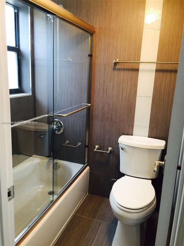 bathroom featuring shower / bath combination with glass door and toilet