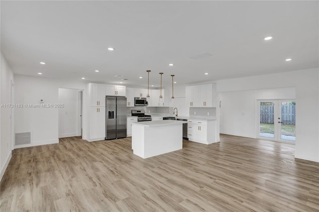 kitchen featuring pendant lighting, a center island, white cabinets, and appliances with stainless steel finishes