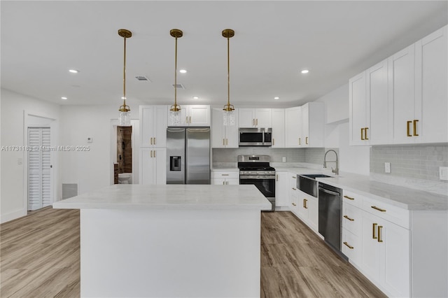 kitchen featuring pendant lighting, white cabinetry, stainless steel appliances, and a kitchen island