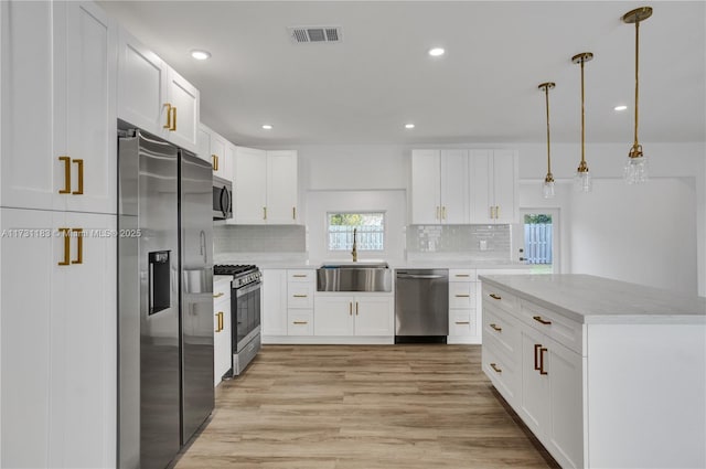 kitchen with sink, decorative light fixtures, appliances with stainless steel finishes, decorative backsplash, and white cabinets