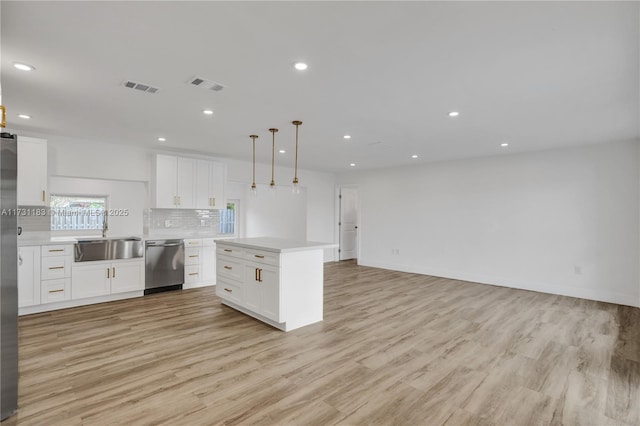 kitchen featuring a kitchen island, white cabinetry, sink, hanging light fixtures, and stainless steel appliances