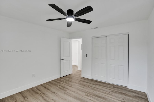 unfurnished bedroom featuring light hardwood / wood-style floors, ceiling fan, and a closet